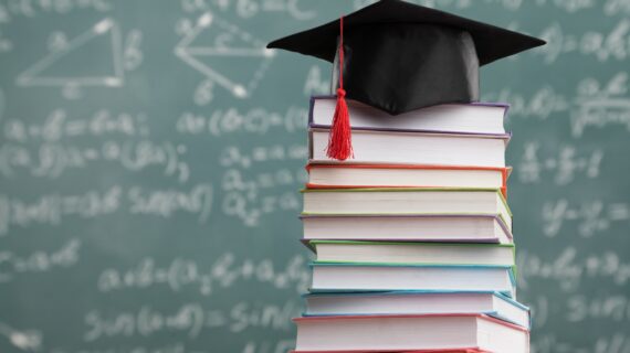 pile of books with academic mortar board on top